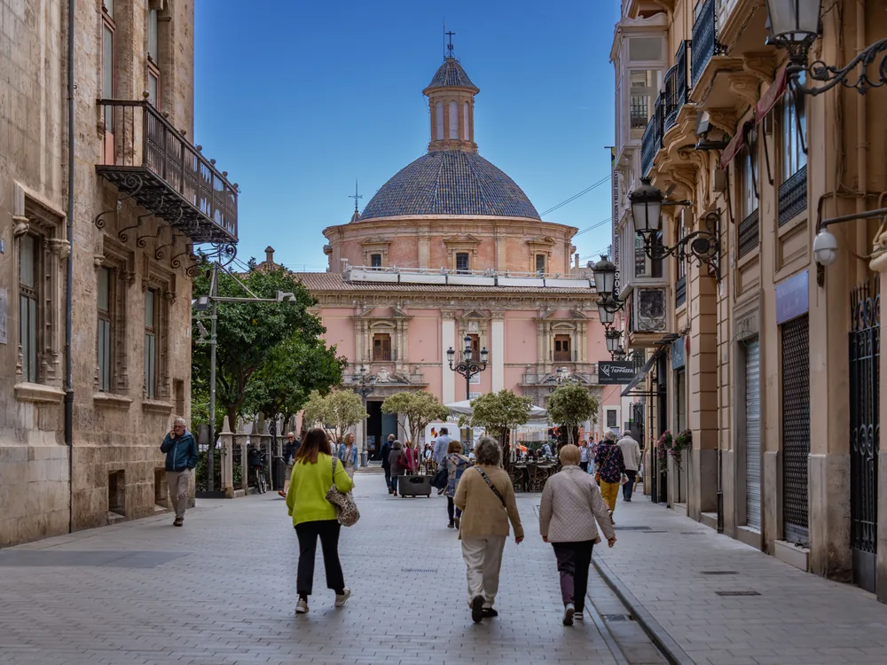 Turistas paseando por una calle del casco histórico de Valencia hacia la basílica de la Virgen de los Desamparados