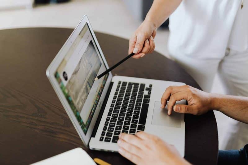 Persona mostrando el diseño de una web de reservas en un portátil