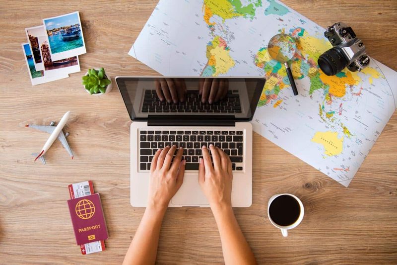 Portátil con mapa del mundo, pasaporte y cámara para planificar viajes