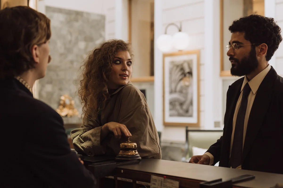 Dos huéspedes hablando con el recepcionista en el mostrador de un hotel durante el check-in