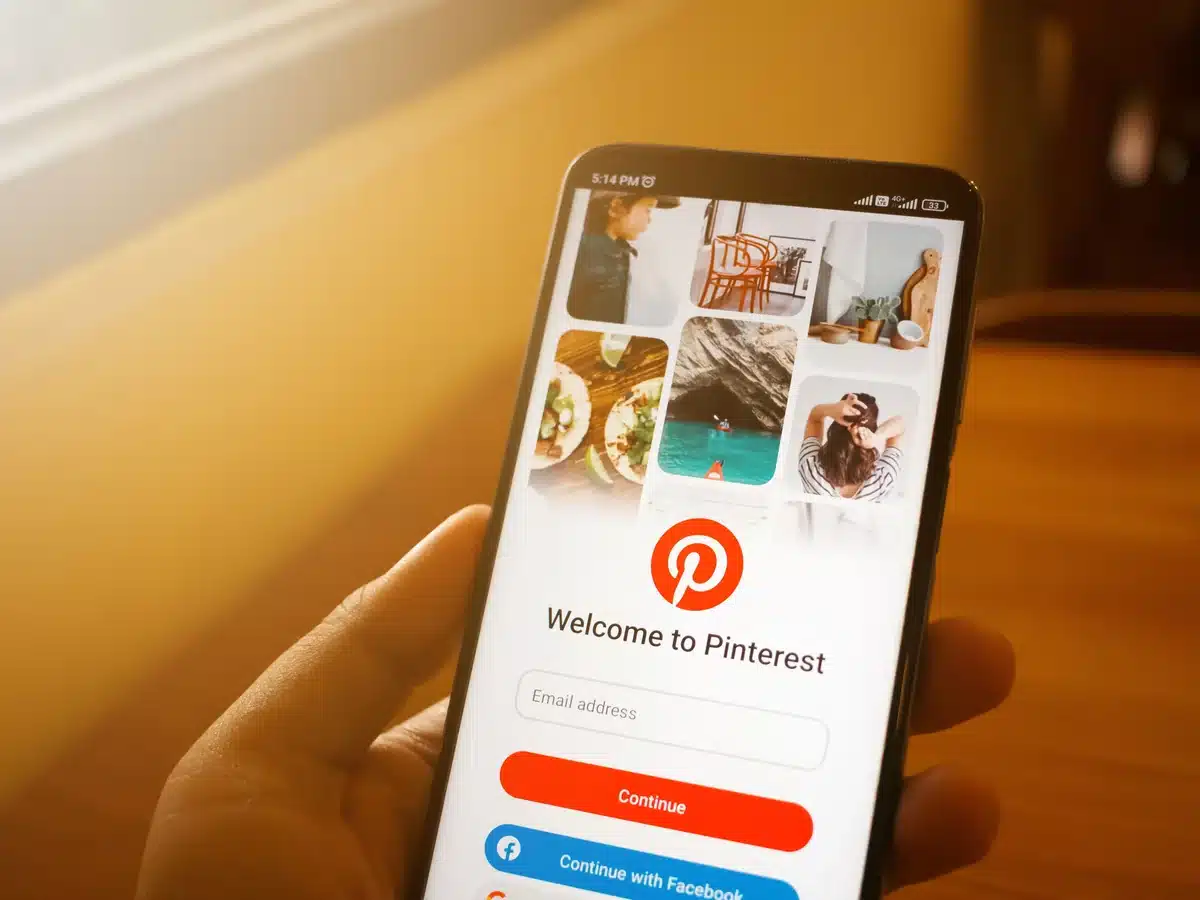 Mano sosteniendo un móvil con la pantalla de bienvenida de Pinterest