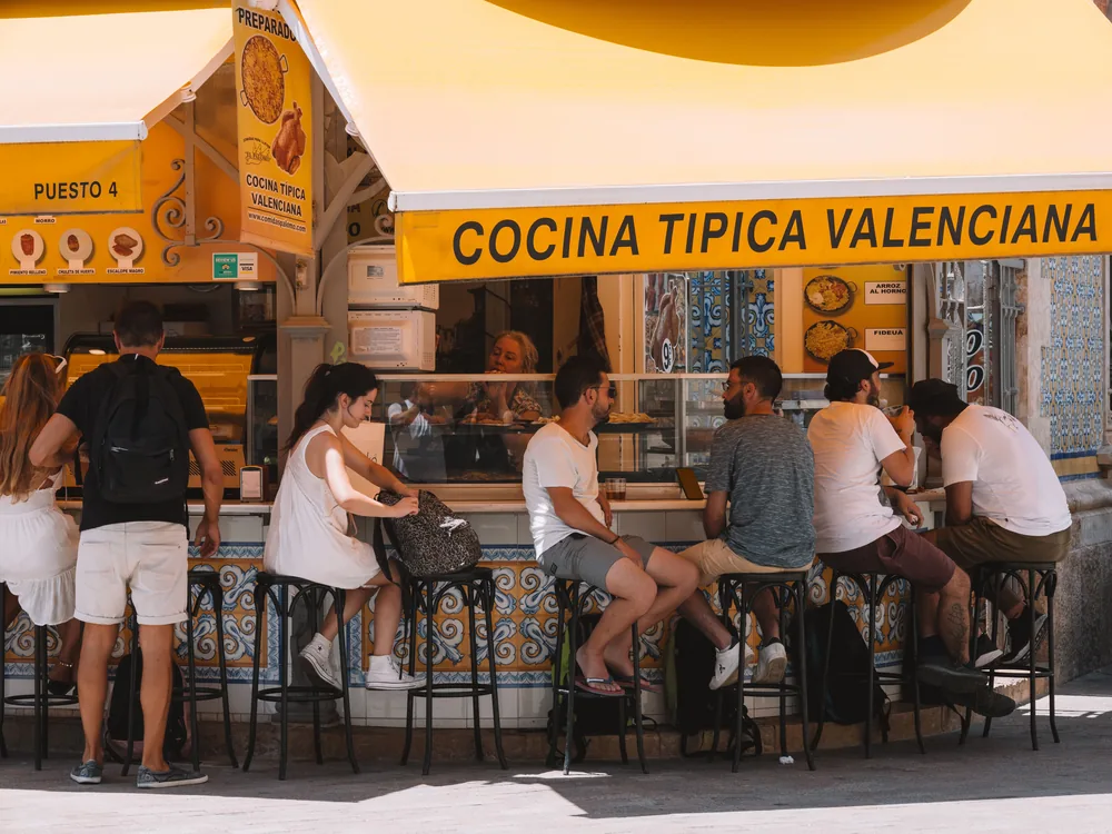 Clientes comiendo en la barra de un puesto de cocina típica valenciana junto al Mercado Central