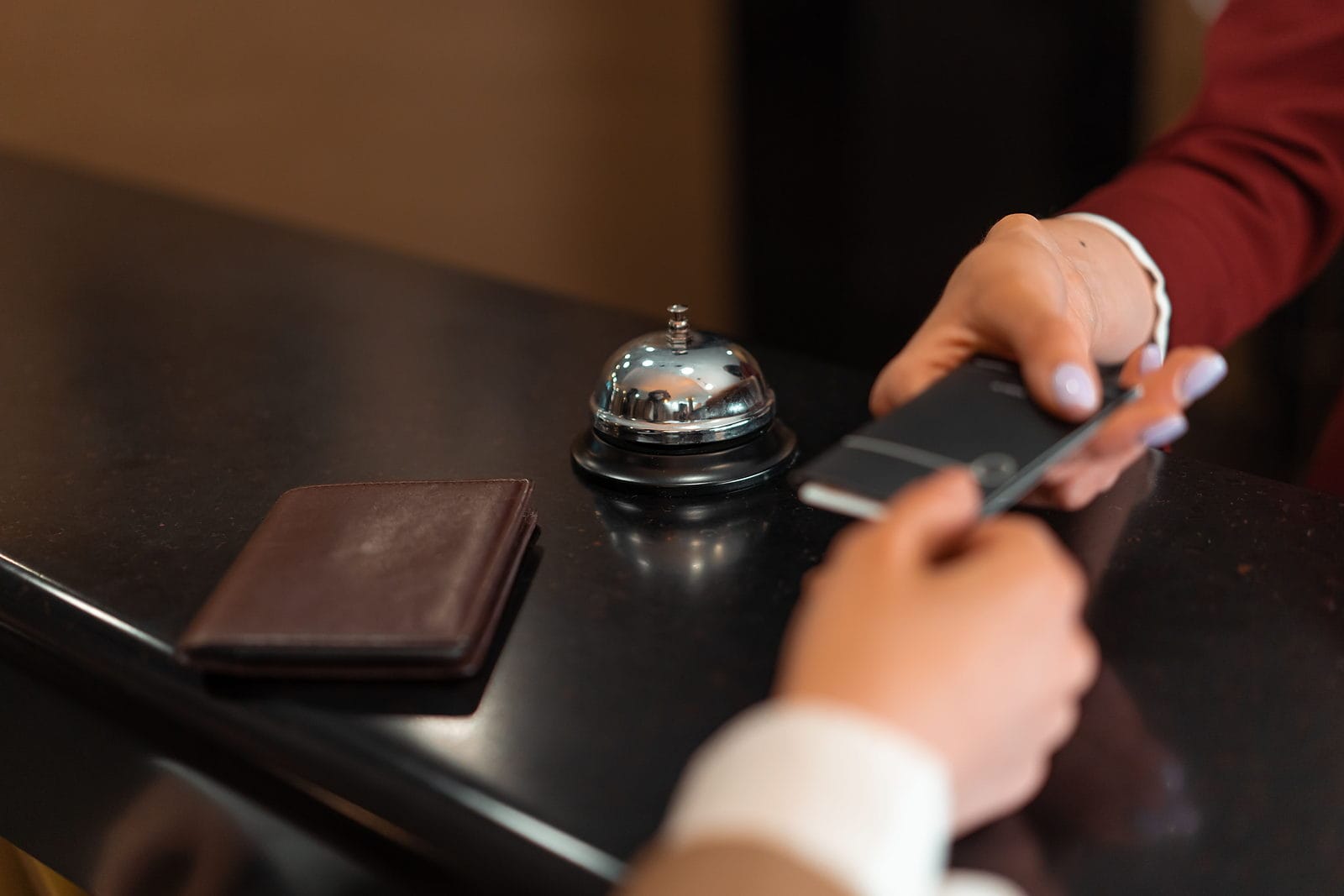 Huésped pagando su reserva con el móvil en el mostrador de un alojamiento